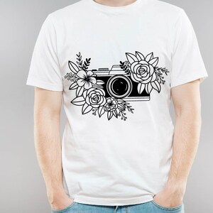 K&ouml;nnte beinhalten: Ein wei&szlig;es T-Shirt mit einer schwarz-wei&szlig;en Illustration einer Kamera, die von Blumen umgeben ist.