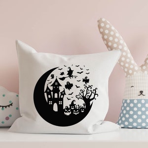 May include: White pillow with a black silhouette of a crescent moon, a haunted house, a witch flying on a broomstick, a tree, and pumpkins. The design is perfect for Halloween.