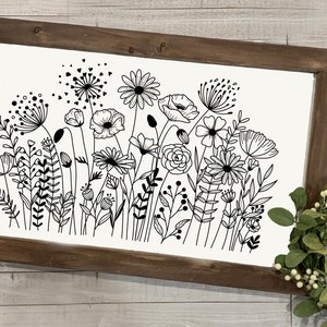 K&ouml;nnte beinhalten: Schwarzwei&szlig;-Linienkunst-Druck eines Blumenstrau&szlig;es mit verschiedenen Blumen und Bl&auml;ttern. Der Druck ist in einem rustikalen braunen Holzrahmen gerahmt.