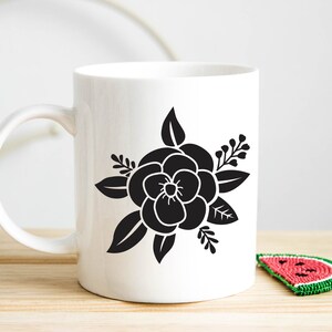 Pode incluir: Caneca de cer&acirc;mica branca com uma silhueta preta de uma flor com folhas. A flor tem cinco p&eacute;talas e um centro.