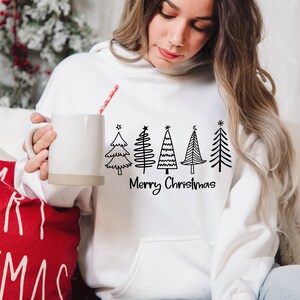 May include: White hoodie with a black and white illustration of a row of Christmas trees and the text "Merry Christmas".