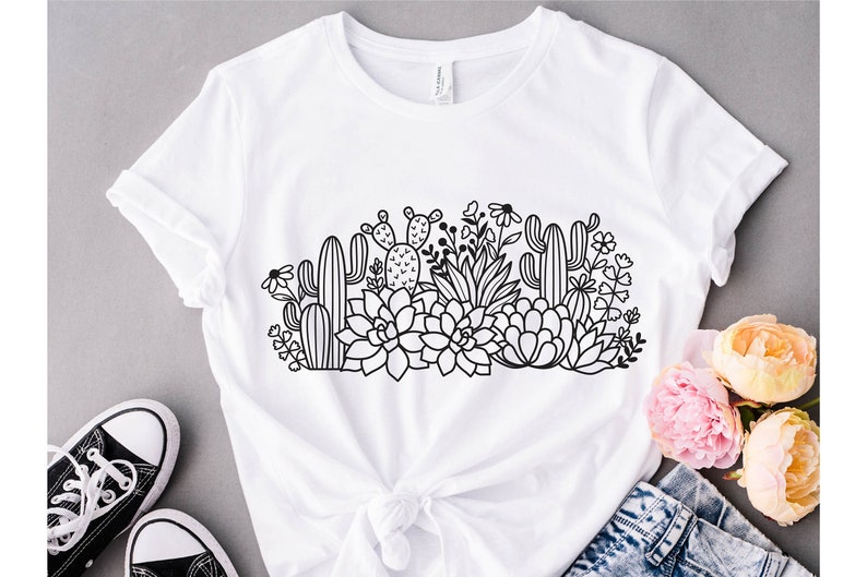 May include: A white t-shirt with a black line drawing of a variety of succulents and cacti. The design features a variety of shapes and sizes of succulents and cacti, as well as some small flowers.