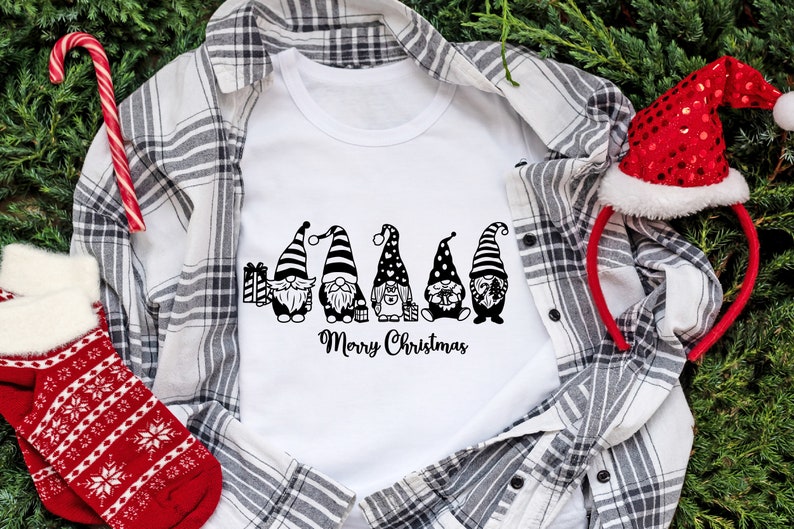 May include: White t-shirt with a black and white graphic of five gnomes holding gifts and the text "Merry Christmas".
