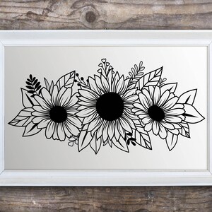 May include: A framed black and white floral print depicting three sunflowers with detailed petals and dark centres. The artwork is set against a light background within a white rectangular frame, suitable for home decor.