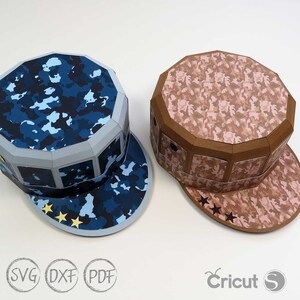 May include: Two papercraft hats with camouflage patterns. One hat is blue and the other is brown. Both hats have a star design on the brim.
