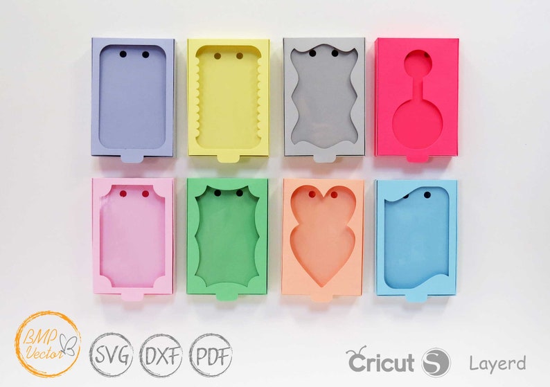 May include: Eight different card-sized boxes with various shapes and colors. The boxes have a cut-out window and two holes for string or ribbon. The boxes are perfect for packaging small gifts or favors.