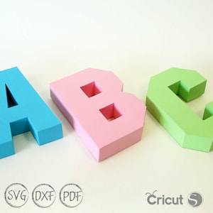以下が含まれることがあります： 紙でできた3次元の文字A、B、C。Aは薄い青色、Bはピンク色、Cは薄い緑色です。