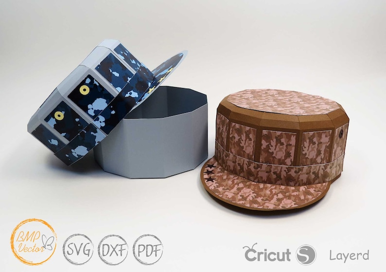 May include: Two papercraft hats, one blue and one brown, with camouflage patterns. The blue hat is open and the brown hat is closed. Both hats have a star design on the brim. The hats are made of paper and are designed to be assembled.