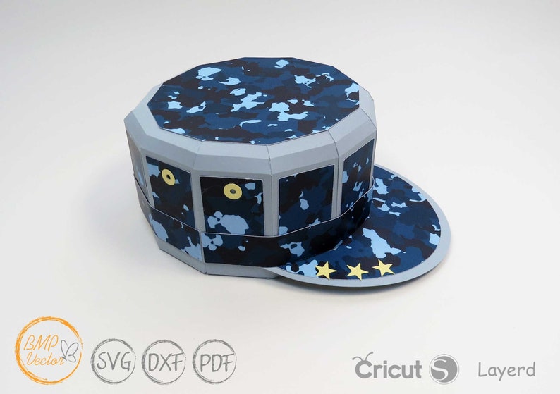 May include: A blue and gray papercraft hat with a camouflage pattern and three gold stars on the brim. The hat is designed to be assembled from a paper model.