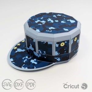 May include: A blue and white camouflage papercraft hat with a brim and a yellow star design. The hat is made of paper and is designed to be assembled.