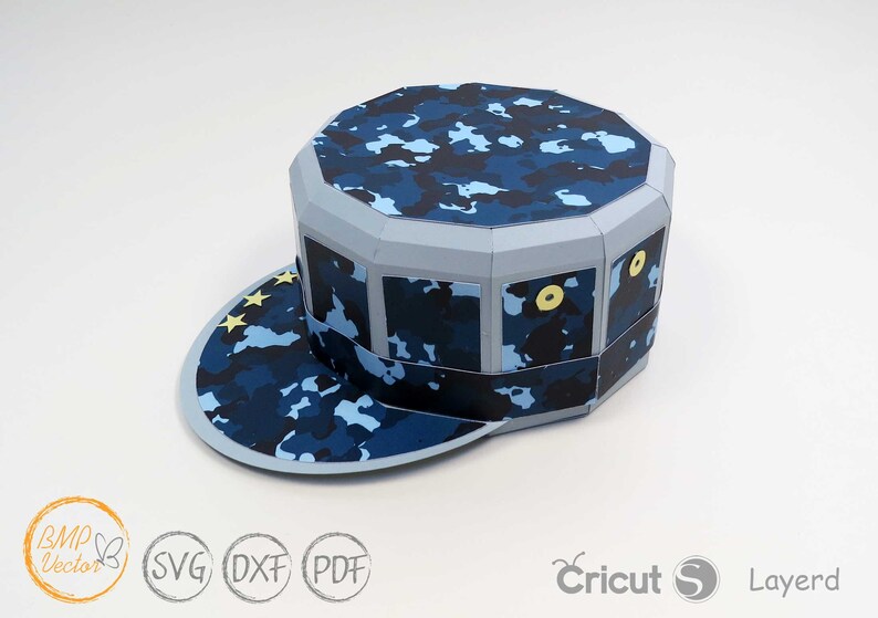 May include: A blue and white camouflage papercraft hat with a brim and a yellow star design. The hat is made of paper and is designed to be assembled.