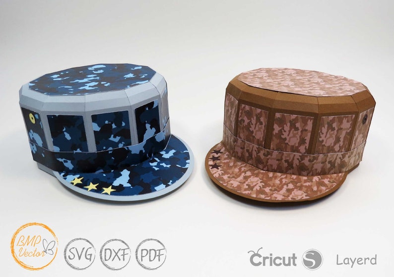 May include: Two papercraft hats in camouflage patterns. One hat is blue and the other is brown. Both hats have a brim and a flat top.