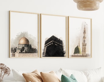 May include: Three framed watercolour paintings of Islamic landmarks. The paintings are hung on a white wall above a white sofa with brown and green cushions. A woven room divider is in the background.