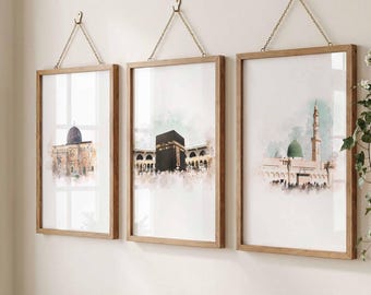 May include: Three framed watercolour prints depicting Islamic landmarks. The prints show the Dome of the Rock, the Kaaba, and the Prophet's Mosque. Each print is in a wooden frame and suspended by a chain.