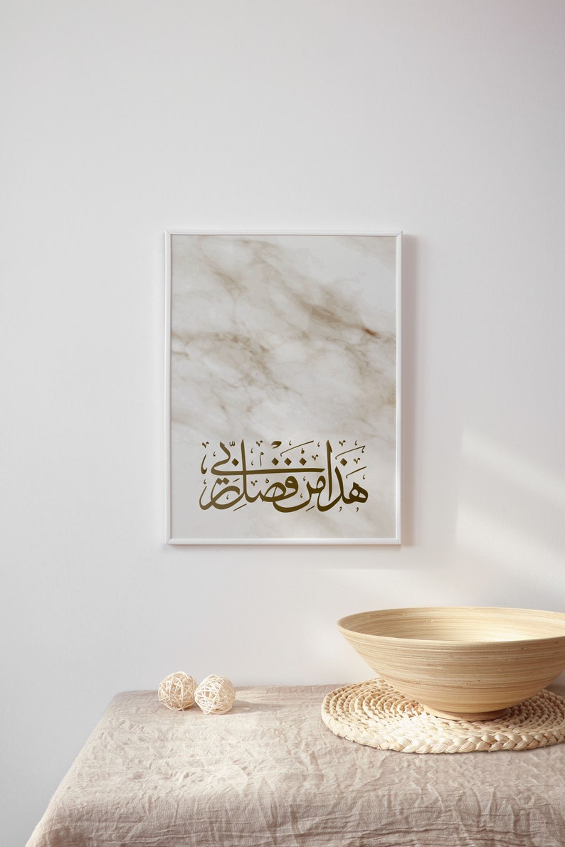 May include: A framed print with a marble background and gold Arabic calligraphy that reads "Masha Allah" in a white frame on a white wall. A wooden bowl and two woven balls are on a beige linen tablecloth.