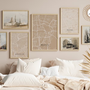 Può includere: Un muro beige con una collezione di stampe incorniciate che mostrano mappe di città e illustrazioni architettoniche. Le stampe sono disposte a griglia e includono mappe della Mecca, Medina, Gerusalemme e altre città. Le stampe sono incorniciate in cornici di legno naturale e hanno un'estetica minimalista.
