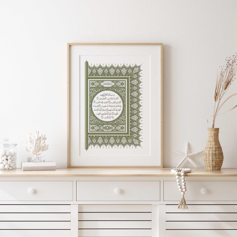 May include: A framed print featuring Islamic calligraphy in green and black on a white background. The calligraphy is surrounded by an elaborate floral border.