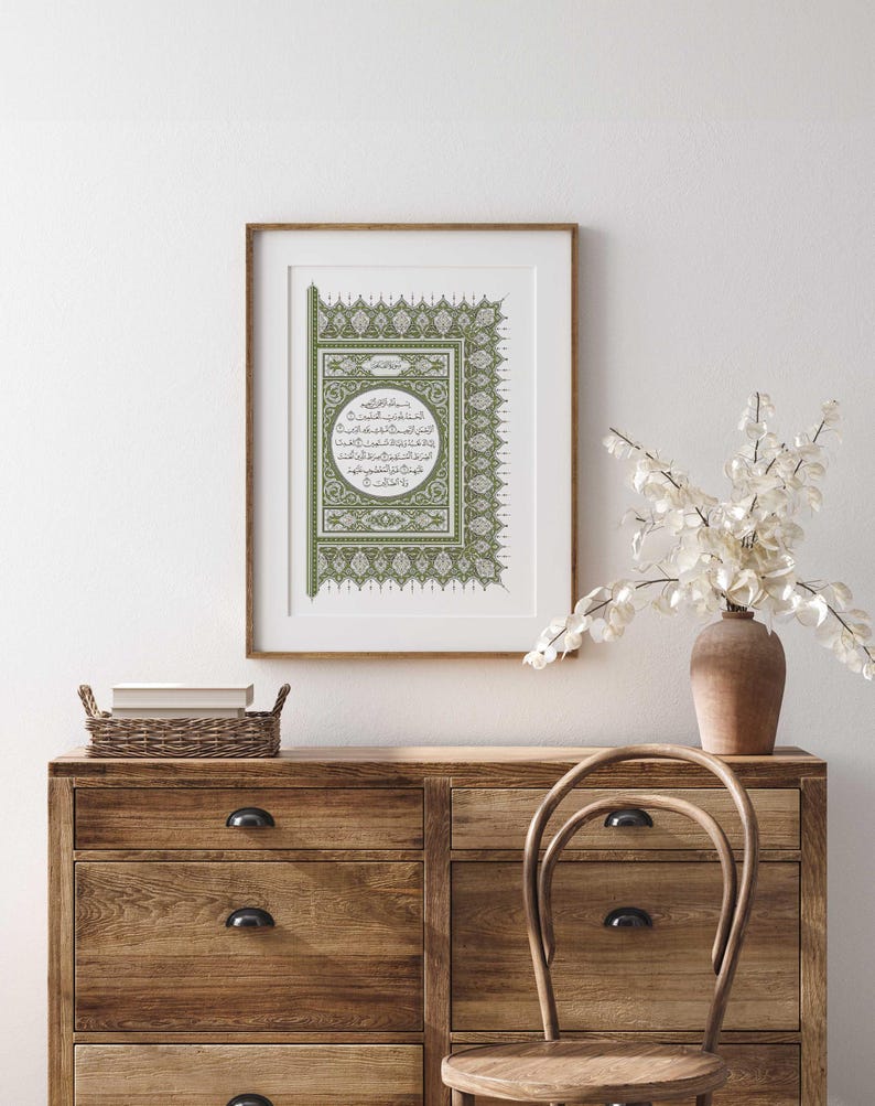 May include: A framed print of an Islamic calligraphy design in green and white. The design features intricate patterns and a circular frame with Arabic text.