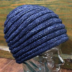 May include: A blue knitted beanie with a ribbed texture. The beanie is made of a soft, stretchy material and has a slouchy fit.