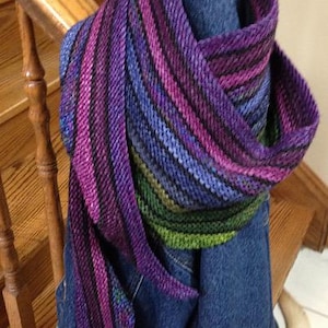 May include: A purple, green, and blue striped knitted scarf draped over a blue denim jacket.