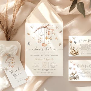 May include: A beach-themed baby shower invitation with a watercolor illustration of a seashell mobile. The invitation includes the text "a beach babe is on the way" and details for the shower, including the date, time, and location. There are also two additional cards for a diaper raffle and a book request for the baby.