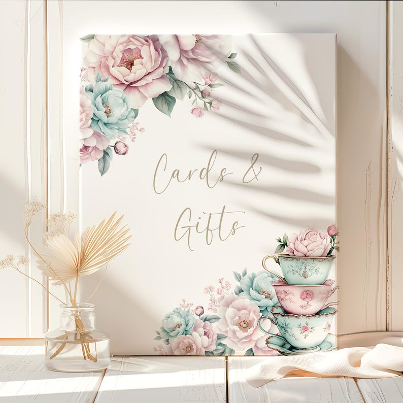 K&ouml;nnte beinhalten: Ein wei&szlig;es Schild mit rosa und blauen Blumendesigns und einem Stapel Teetassen. Das Schild lautet "Cards & Gifts".