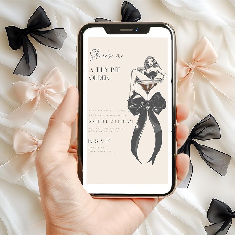 Puede incluir: Una invitaci&oacute;n digital en la pantalla de un tel&eacute;fono inteligente con una ilustraci&oacute;n en blanco y negro de una mujer sentada en una copa de martini con un lazo negro. El texto de la invitaci&oacute;n dice "She's a Tiny Bit Older" e incluye detalles para una fiesta de cumplea&ntilde;os.