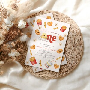 Könnte beinhalten: Zwei Einladungskarten mit einem verspielten Design. Die Karten zeigen Illustrationen von Fast-Food-Artikeln, darunter Pommes Frites, Nuggets und ein Getränk, sowie den Text "Our Little Nugget is One". Die Einladung enthält Veranstaltungsdetails.
