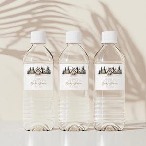 May include: Three clear plastic water bottles with white caps. Each bottle has a label with a watercolor illustration of houses and trees, with the text "Welcome to Jordana's Baby Shower" and a date.