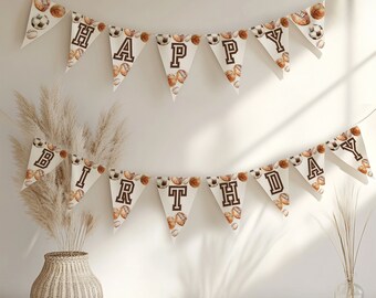 May include: A white banner with brown letters spelling "Happy Birthday" and a sports theme. The banner is decorated with brown and white sports balls.