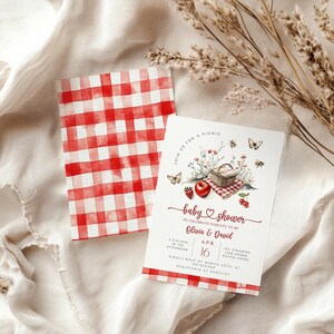 May include: A baby shower invitation with a red and white checkered pattern. The invitation features watercolor illustrations of a picnic basket, fruit, and flowers. The text reads "baby shower" and includes event details.