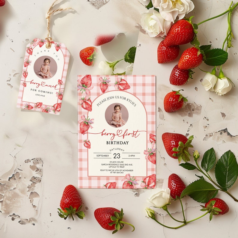 May include: A pink and white gingham patterned invitation with a watercolor illustration of strawberries. The invitation is for a first birthday party and says "Berry First Birthday" with the date September 23rd.