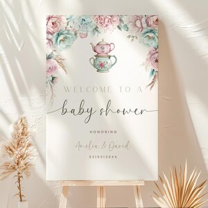 K&ouml;nnte beinhalten: Ein wei&szlig;es Schild mit floralen Illustrationen und einem Teetassen-Design. Das Schild lautet "Willkommen zu einer Babyparty zu Ehren von Amelia & David 02103120XX".
