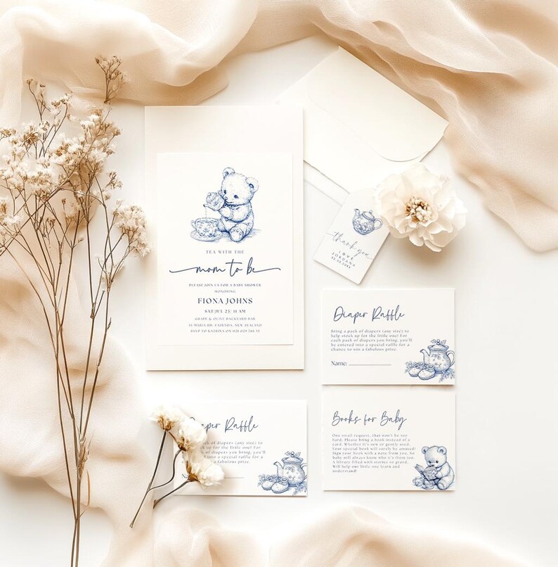 Peut inclure: Invitation de f&ecirc;te pr&eacute;natale bleu et blanc avec un ours en peluche buvant du th&eacute;. L'invitation indique "Tea with the Mom to Be". Il y a aussi des cartes pour une tombola de couches et des livres pour b&eacute;b&eacute;.