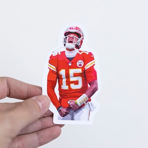 May include: A red, white, and yellow sticker of a football player wearing a helmet and jersey with the number 15. The player is looking up and has a determined expression on his face.