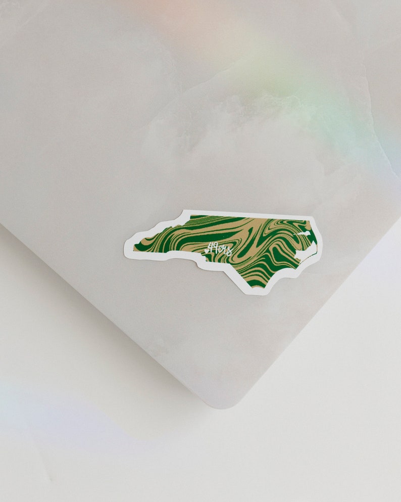 May include: A green and brown swirl sticker of the state of North Carolina with the word "49ers" written in white.