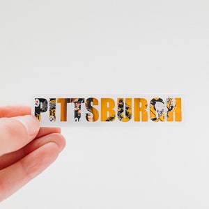 May include: A white sticker with the word "PITTSBURGH" written in yellow letters. The letters are made up of a collage of images, including a football player in a black and yellow uniform.