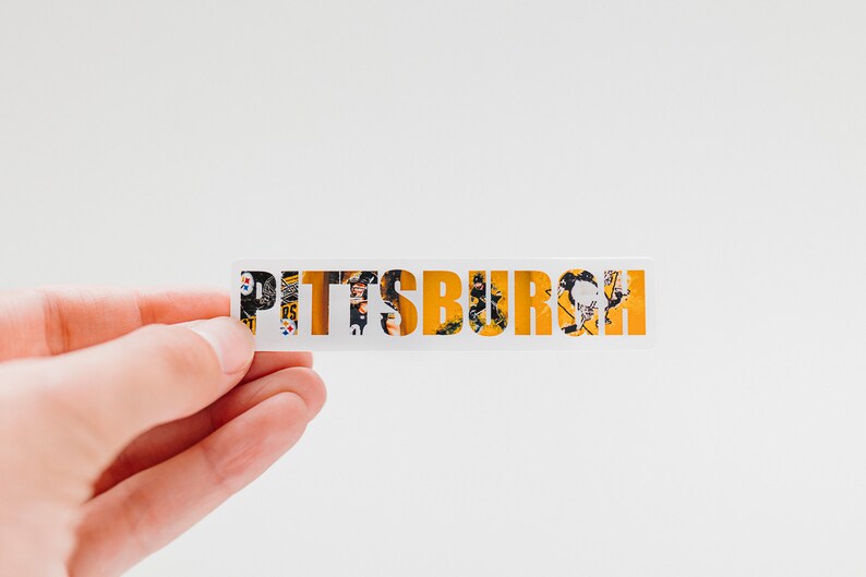 May include: A white sticker with the word "PITTSBURGH" written in yellow letters. The letters are made up of a collage of images, including a football player in a black and yellow uniform.