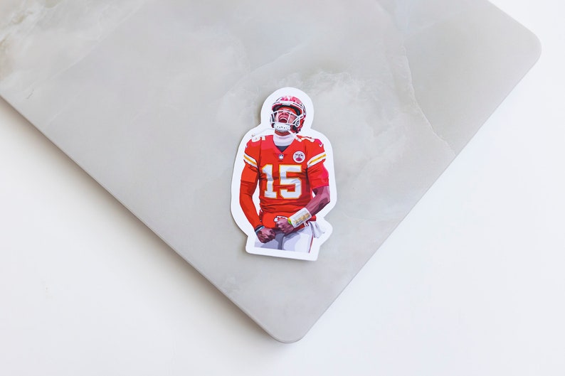 May include: A sticker featuring a football player wearing a red and white jersey with the number 15. The player is in a celebratory pose with his arms raised.