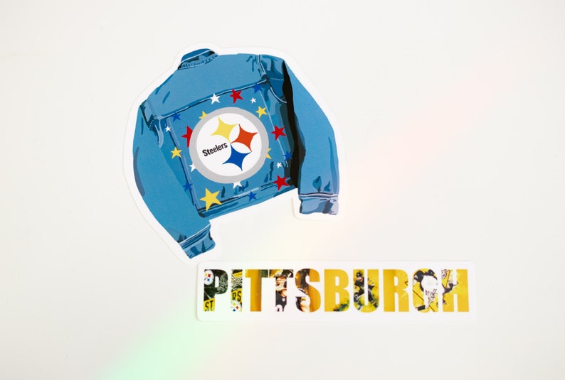 May include: A blue denim jacket with a Pittsburgh Steelers logo and yellow stars. The word "Pittsburgh" is written in yellow letters on a white background.