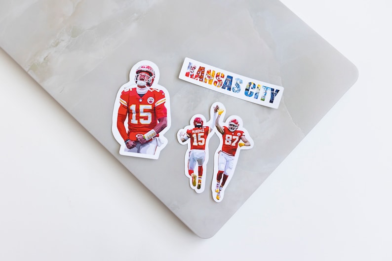 May include: Three stickers featuring images of American football players wearing red and white uniforms. The stickers feature the numbers 15 and 87. One sticker has the text "KANSAS CITY" in colorful letters.
