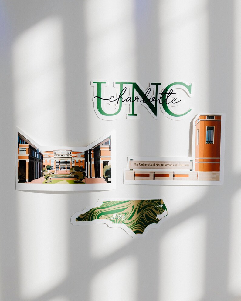 May include: A set of four stickers featuring the University of North Carolina at Charlotte. The stickers include the school's logo, a building on campus, the school's name, and a map of North Carolina.