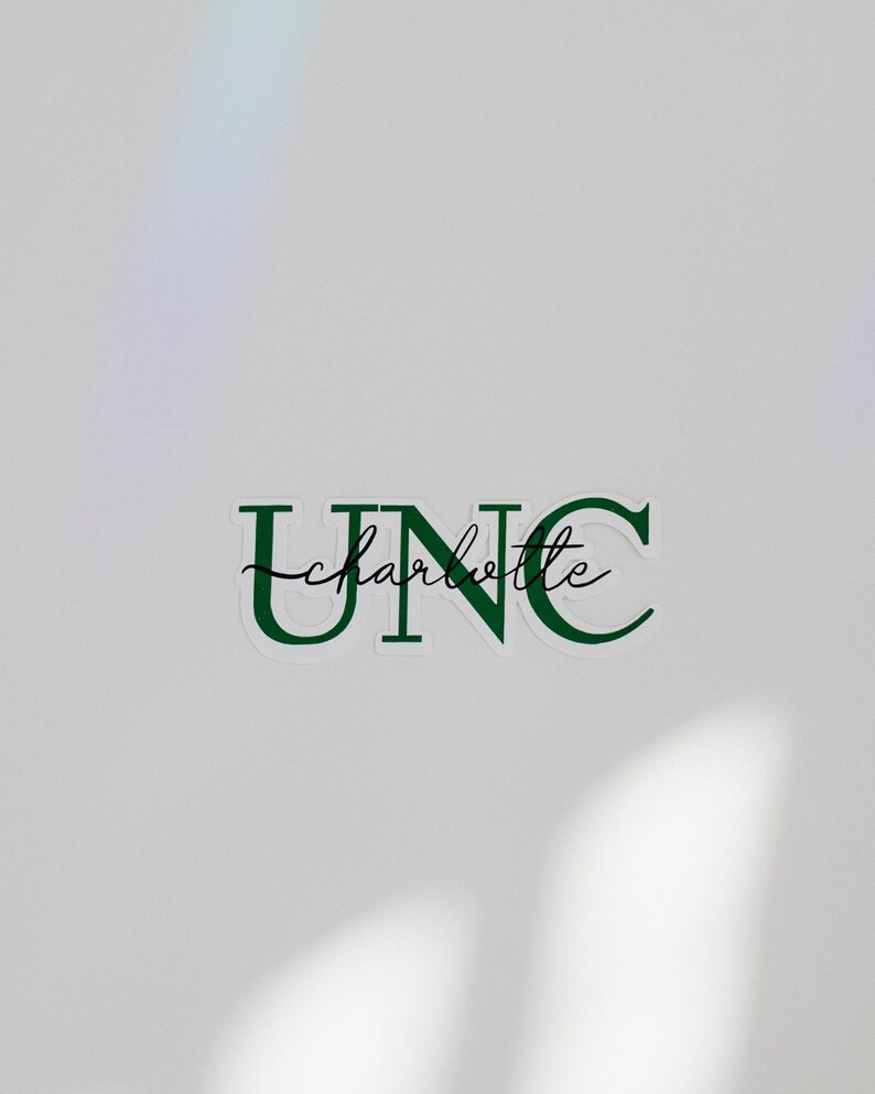 May include: A white sticker with green lettering that reads "UNC charlotte" in a cursive font.