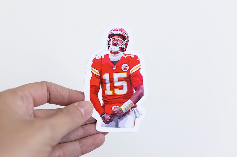 May include: A red, white, and yellow sticker of a football player wearing a helmet and jersey with the number 15. The player is looking up and has a determined expression on his face.