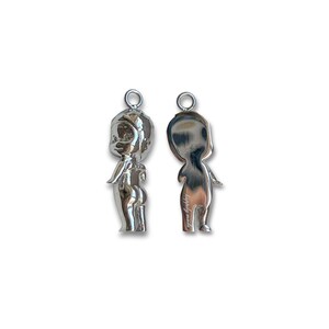 K&ouml;nnte beinhalten: Zwei silberfarbene Anh&auml;nger in Form einer stilisierten Figur, einer mit Vorder- und einer mit R&uuml;ckseite. Jeder Anh&auml;nger hat oben eine kleine Schlaufe zum Aufh&auml;ngen. Der vordere Anh&auml;nger hat detaillierte Merkmale, w&auml;hrend der hintere Anh&auml;nger glatt ist.