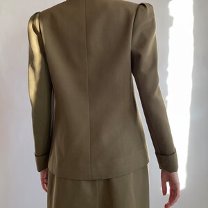 May include: A brown blazer with a fitted silhouette and puffed sleeves. The blazer has a double-breasted closure and a skirt.