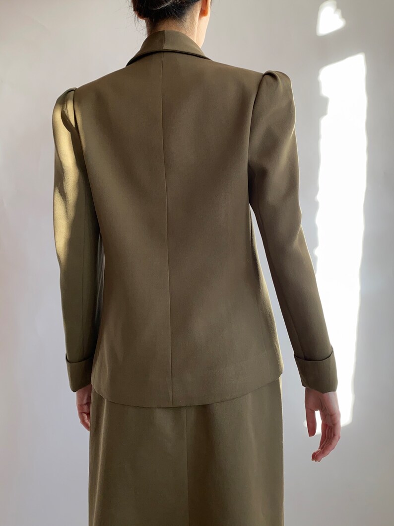 May include: A brown blazer with a fitted silhouette and puffed sleeves. The blazer has a double-breasted closure and a skirt.