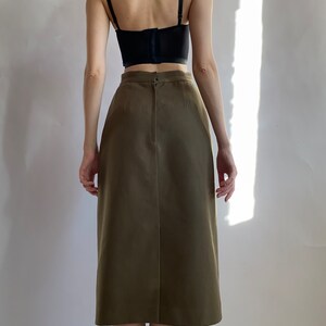May include: A brown midi skirt with a back zip fastening. The skirt is made from a smooth, woven fabric.