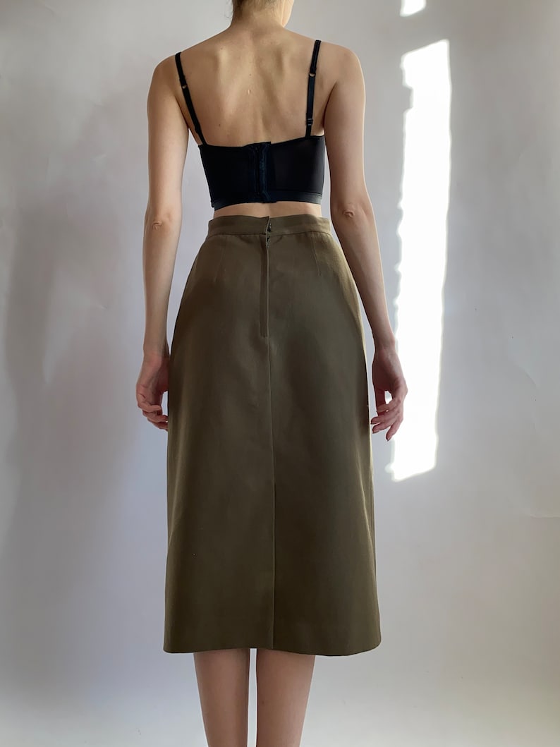 May include: A brown midi skirt with a back zip fastening. The skirt is made from a smooth, woven fabric.
