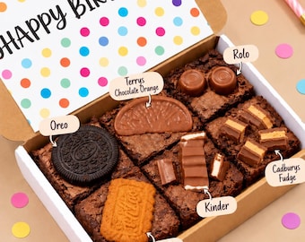 May include: A cardboard gift box containing six chocolate brownies topped with various candies, including an Oreo, Terry's Chocolate Orange, Rolo, Kinder, Biscoff, and Cadbury's Fudge. The lid features colorful polka dots and the text Happy Birthday.